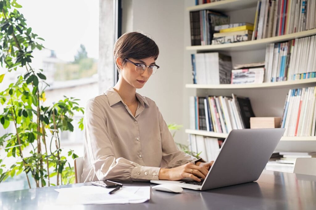 Woman sitting at computer and typing. Learn how to change Instagram password.