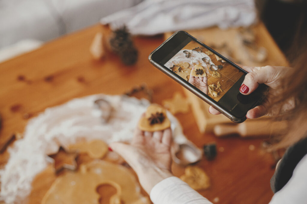 Woman holding phone and taking photo of gingerbread christmas