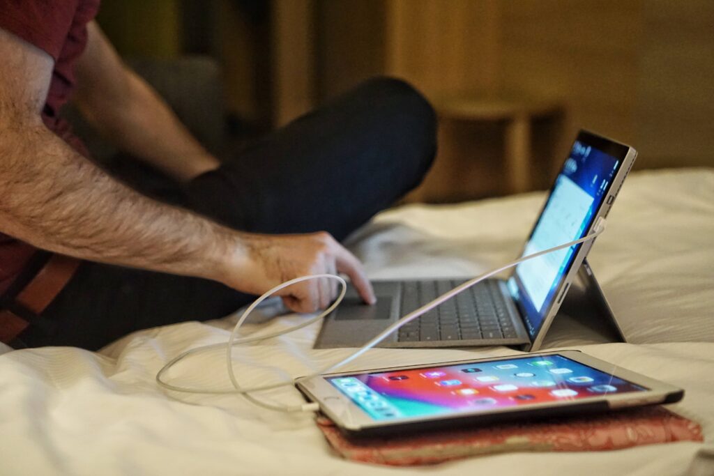 Man sitting by laptop with turned on phone.