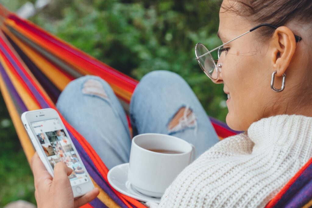 Girl drinking tea and looking at mobile phone.